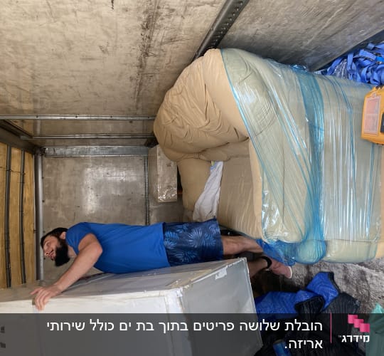 אדם מזיז מקרר במשאית עם רצועות כחולות